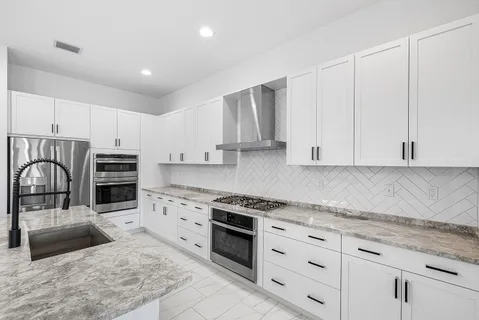 a kitchen with granite countertop a stove sink and refrigerator