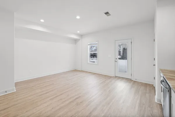 a view of kitchen with stainless steel appliances refrigerator oven and white cabinets with wooden floor