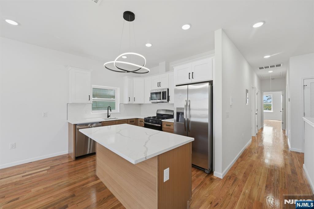 68 Sherman Avenue Newark, NJ 07114 - Photo 23 of 37 a kitchen with stainless steel appliances a refrigerator and a wooden floor