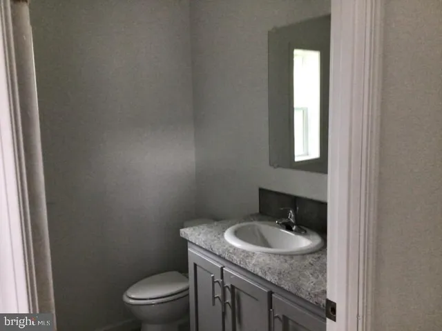 a bathroom with a granite countertop sink and a toilet