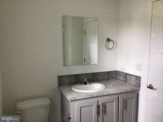 a bathroom with a granite countertop sink and a toilet