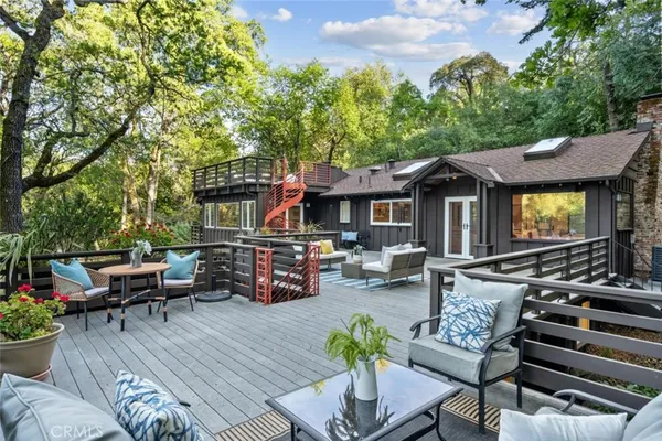 a view of a patio with couches and table and chairs with wooden floor and fence