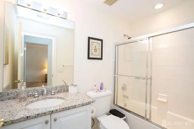a bathroom with a granite countertop sink mirror vanity and toilet