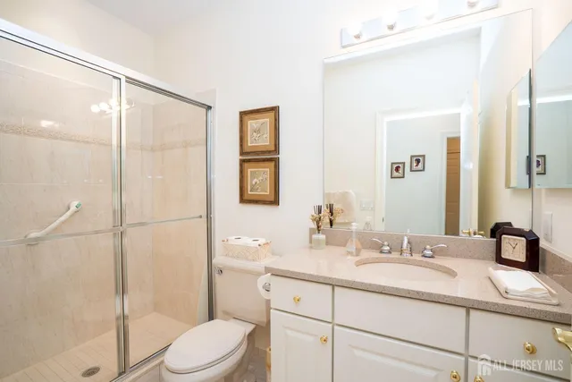 a bathroom with a granite countertop sink toilet a mirror a vanity and shower