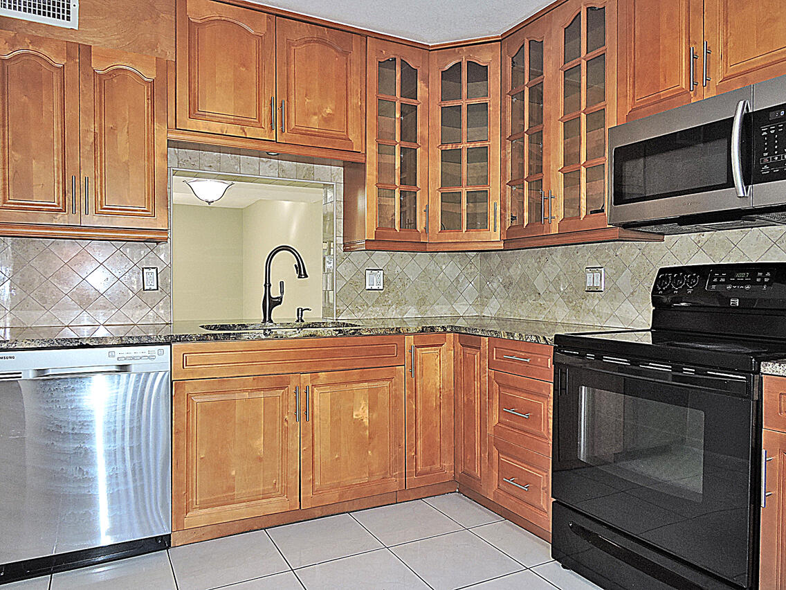 5040 Society Place East, Unit E West Palm Beach, FL 33415 - Photo 3 of 26 a kitchen with stainless steel appliances granite countertop a stove and a microwave