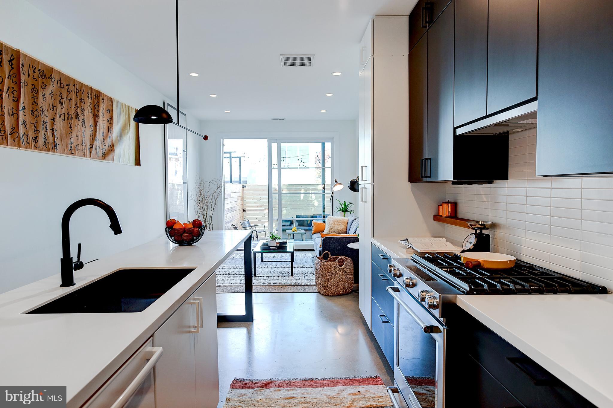 443 Ridge Street Northwest Washington, DC 20001 - Photo 14 of 47 a kitchen with stainless steel appliances a sink dishwasher a stove a microwave oven with a dining table and chairs with wooden floor