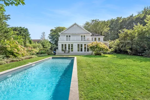 a view of house with garden and tall trees