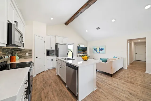a kitchen that has a lot of cabinets a sink and wooden floor