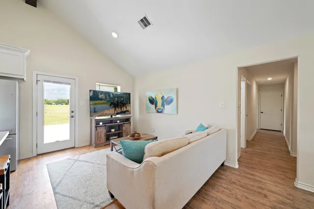 a living room with stainless steel appliances furniture and a flat screen tv