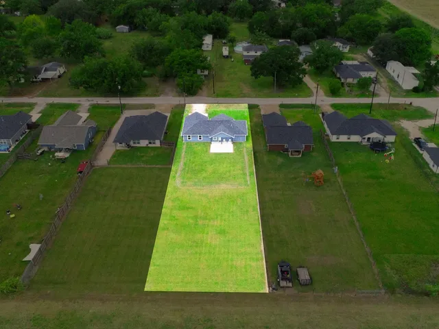 an aerial view of residential houses with outdoor space and trees
