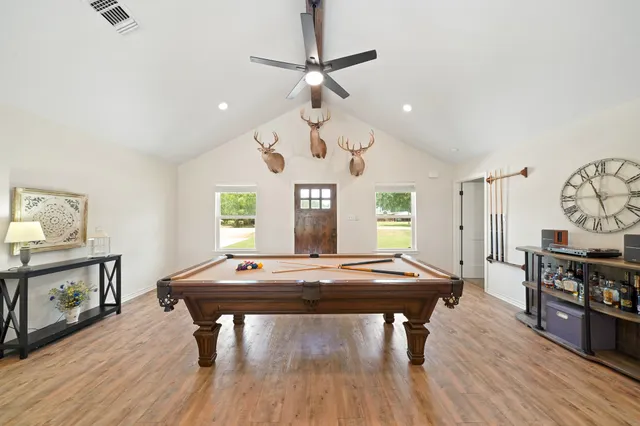a room with wooden floor pool table and windows