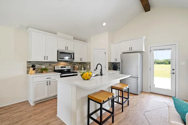 a kitchen with stainless steel appliances a stove a refrigerator a microwave a sink and white cabinets