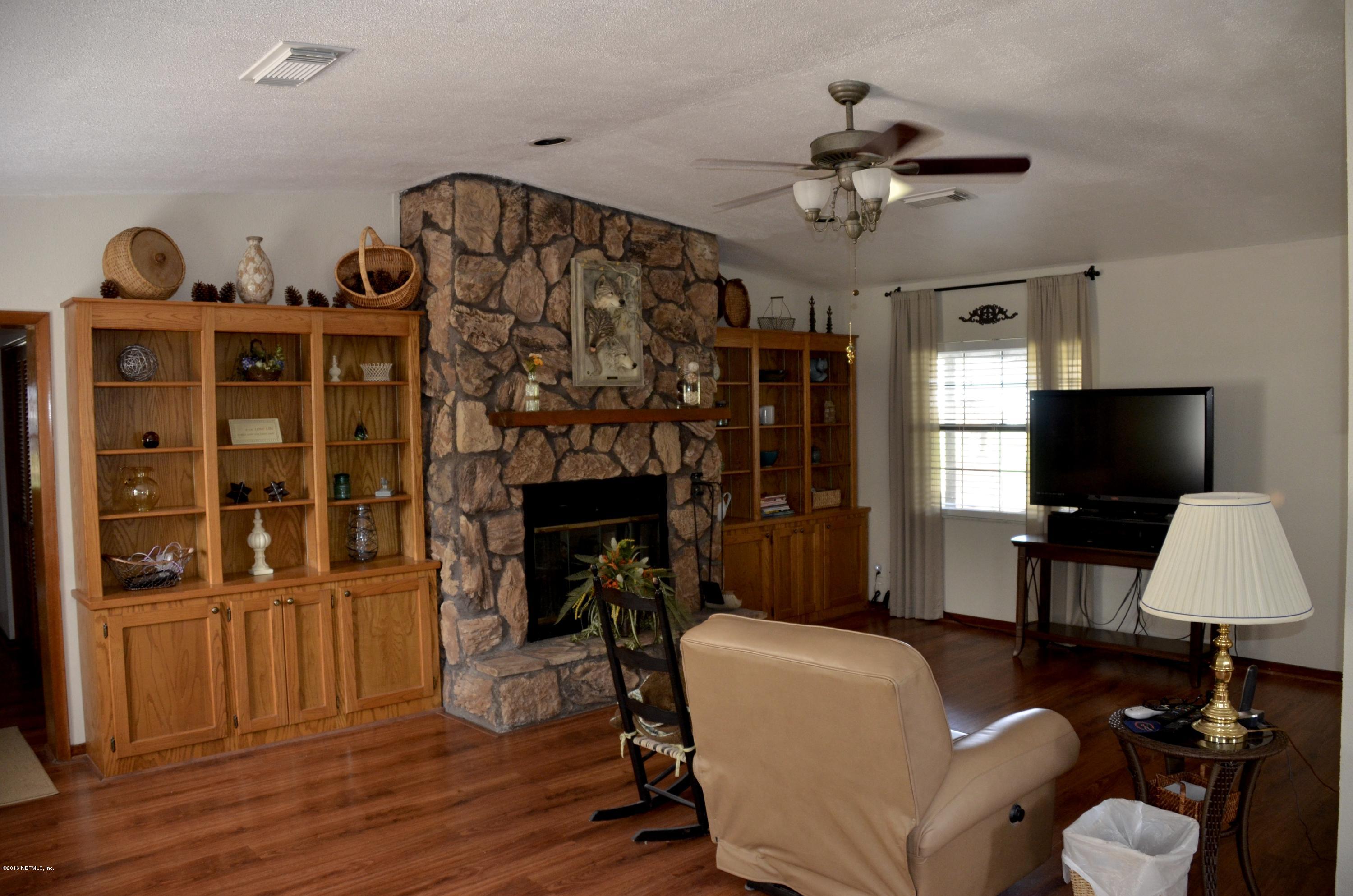 540516 Lem Turner Road Callahan, FL 32011 - Photo 11 of 26 a living room with furniture a fireplace and a flat screen tv