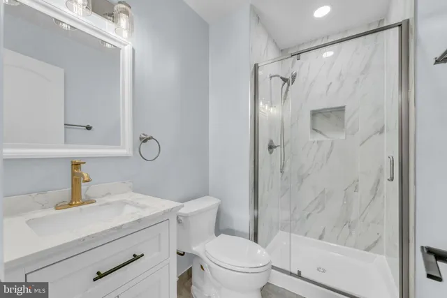 a bathroom with a shower sink vanity mirror and toilet