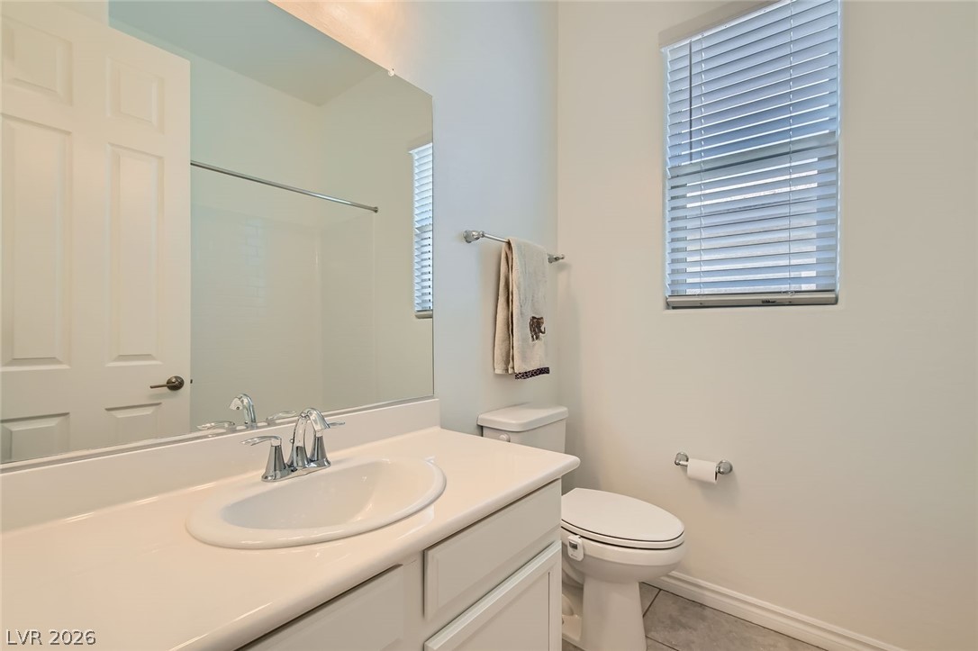 498 Pebble Run Avenue Henderson, NV 89011 - Photo 17 of 47 This bright bathroom features a spacious vanity with a sleek sink, complemented by a large mirror and a window with blinds.