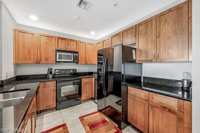 2745 First Street, Unit 104 Fort Myers, FL 33916 - Photo 8 of 39 Kitchen featuring light tile patterned flooring, dark stone counters, and black appliances