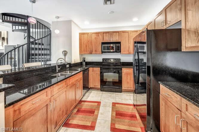 2745 First Street, Unit 104 Fort Myers, FL 33916 - Photo 9 of 39 Kitchen with dark stone counters, black appliances, pendant lighting, and light tile patterned floors