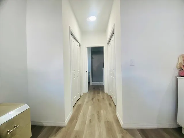 a view of a hallway with wooden floor and a bathroom