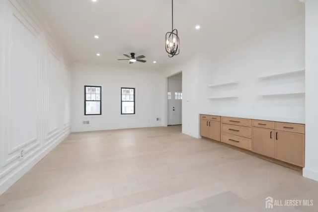 a view of an empty room with chandelier fan and windows