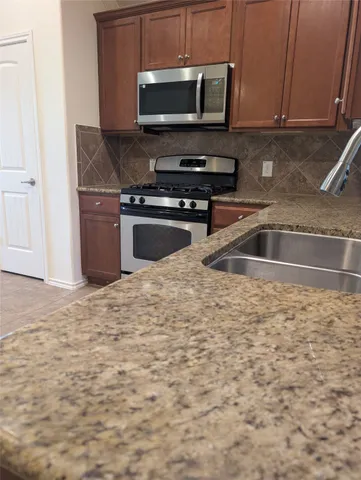 a kitchen with granite countertop a sink and a stove top oven with wooden floor