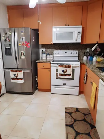 a kitchen with stainless steel appliances granite countertop a refrigerator a stove and a sink