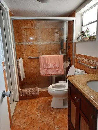 a bathroom with a granite countertop sink toilet and shower