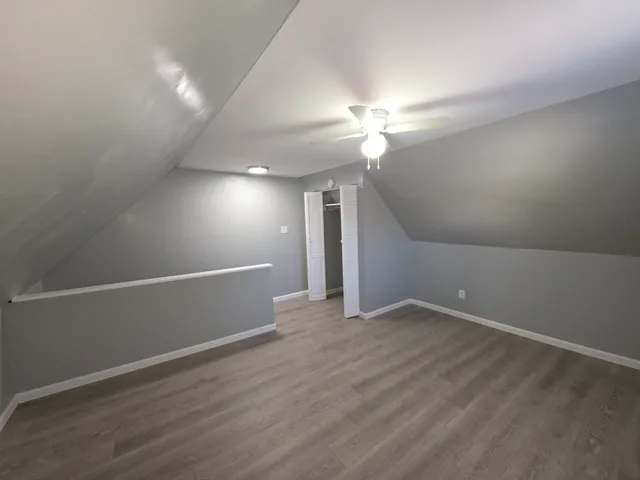 an empty room with wooden floor and fan