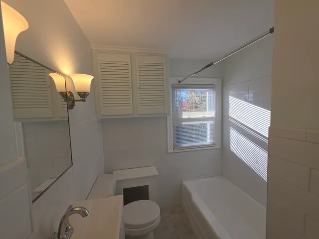 a white toilet sitting next to a bathroom sink and tub