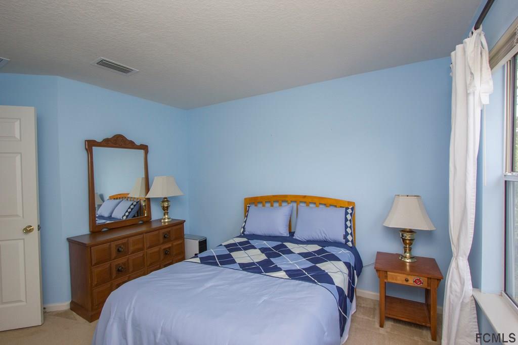 3 Riddle Place Palm Coast, FL 32164 - Photo 23 of 47 a bedroom with a bed and a lamp on the dresser