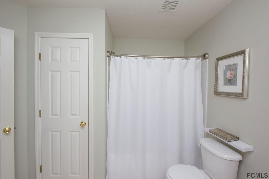 3 Riddle Place Palm Coast, FL 32164 - Photo 25 of 47 a white toilet sitting next to a shower curtain
