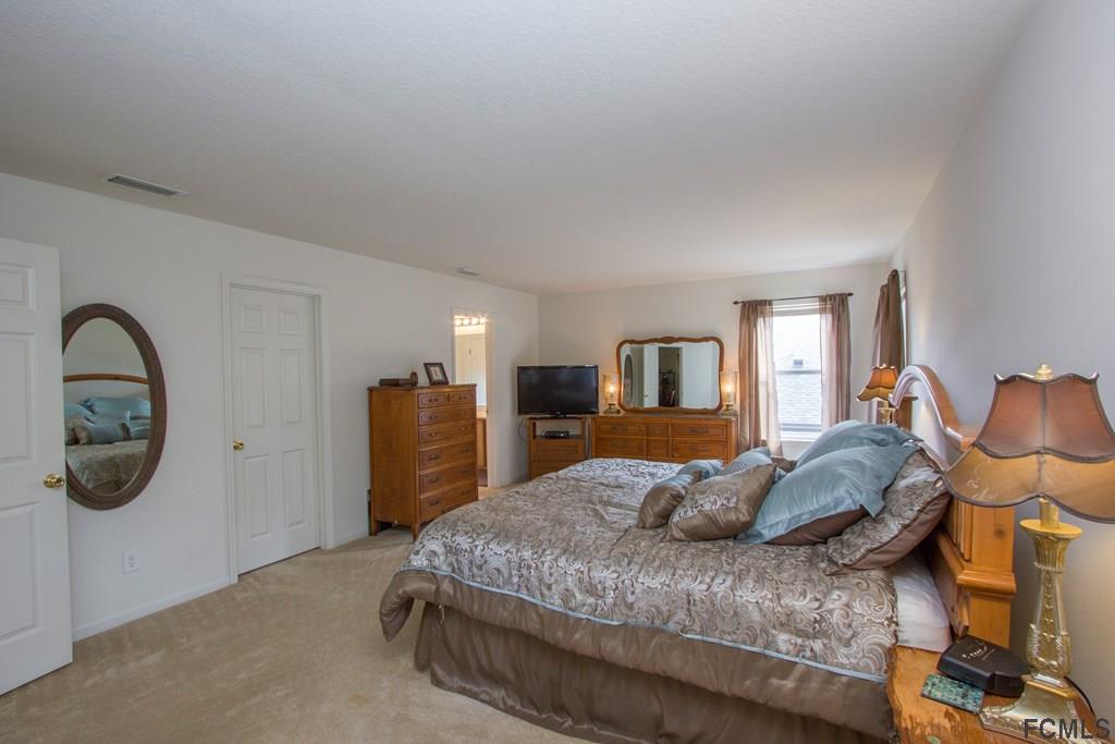 3 Riddle Place Palm Coast, FL 32164 - Photo 32 of 47 a bedroom with a bed and a dresser next to it