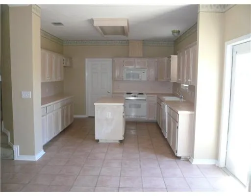 a kitchen with white cabinets and appliances