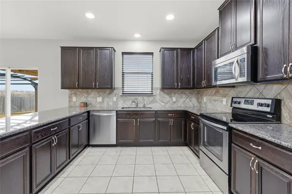 a kitchen with stainless steel appliances granite countertop wooden cabinets a stove top oven a sink and dishwasher