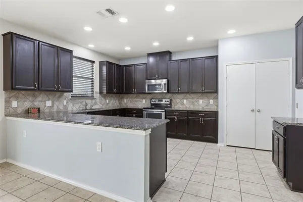 a kitchen with kitchen island granite countertop wooden cabinets a stove a sink and a refrigerator