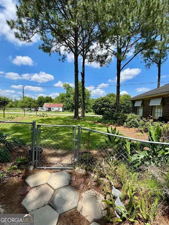 a view of a garden with a tree in front of the house