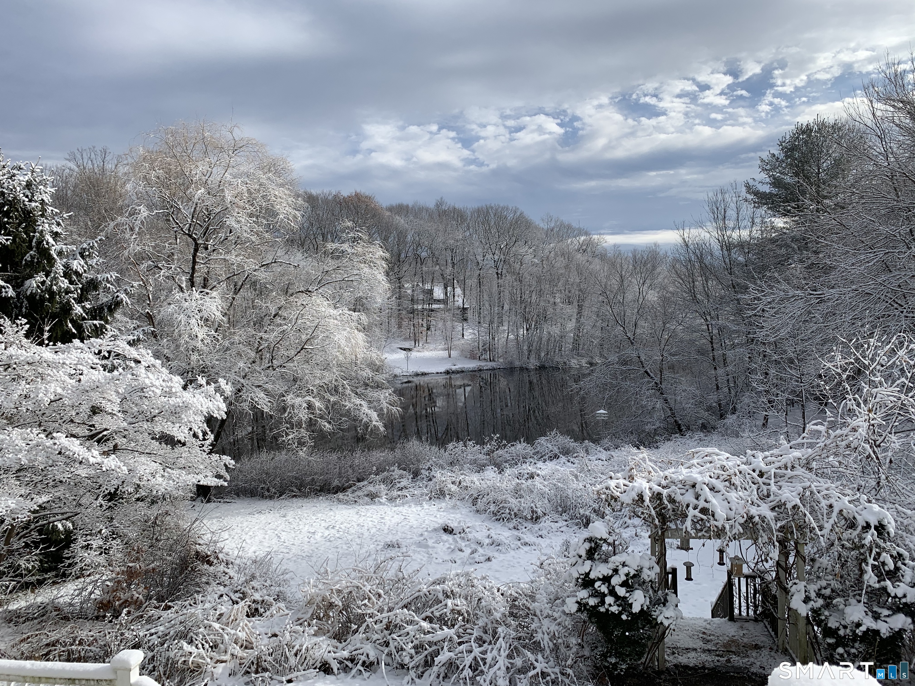 50 Turkey Meadow Road Trumbull, CT 06611 - Photo 38 of 40 Winter: A serene winter scene unfolds as snow blankets the yard and the lake glistens with icy stillness. Bare trees and soft light create a tranquil, storybook setting right outside your door.