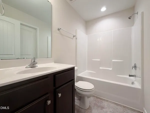 a bathroom with a bathtub shower sink vanity mirror and toilet