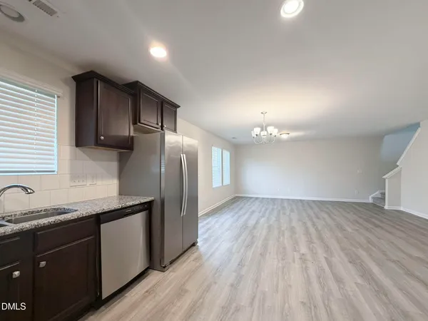a kitchen with granite countertop stainless steel appliances a sink cabinets and wooden floor