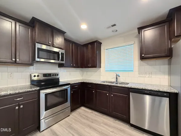 a kitchen with granite countertop wooden cabinets stainless steel appliances and a sink