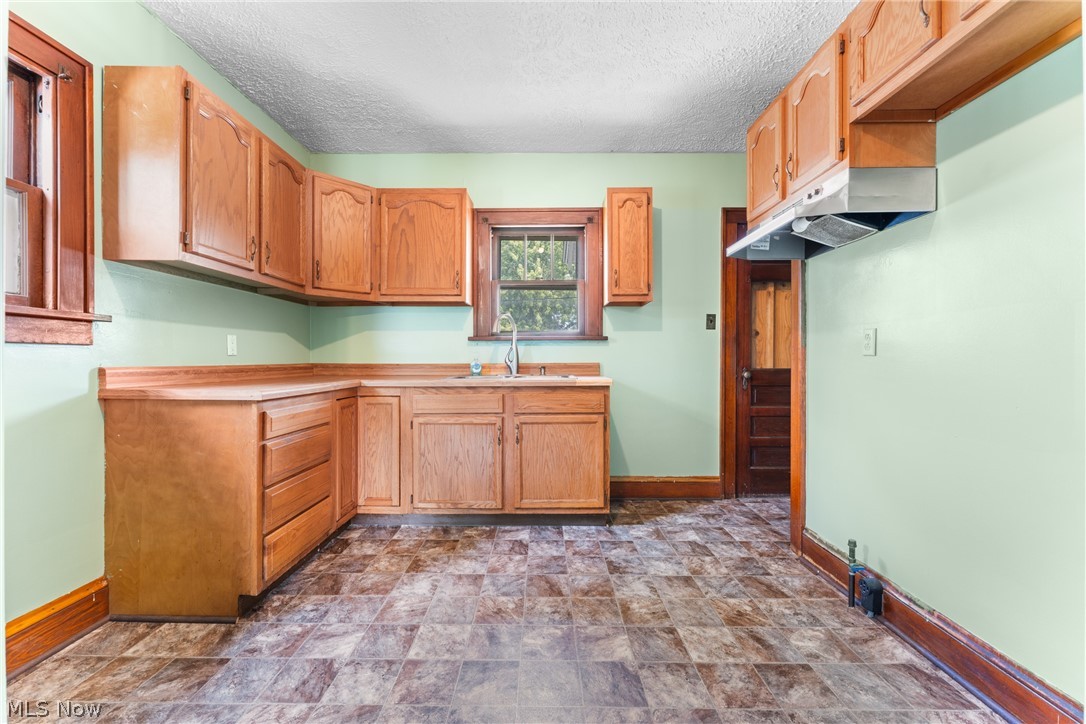 16 South State Street Rittman, OH 44270 - Photo 13 of 27 Kitchen featuring stone finish floors, under cabinet range hood, a textured ceiling, and light countertops