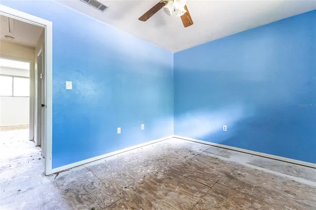 an empty room with ceiling fan and window