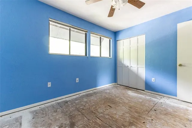 an empty room with windows and fan