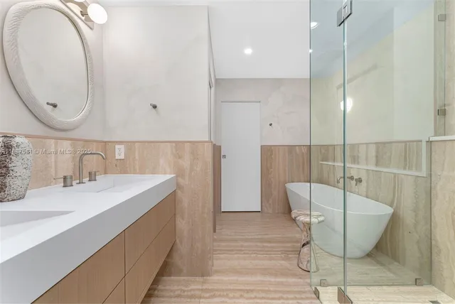 a bathroom with a tub a sink and wooden floor