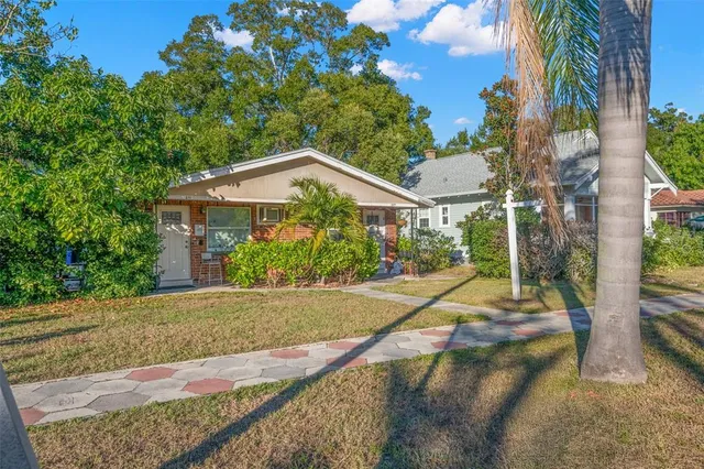 a view of a house with a yard and large tree