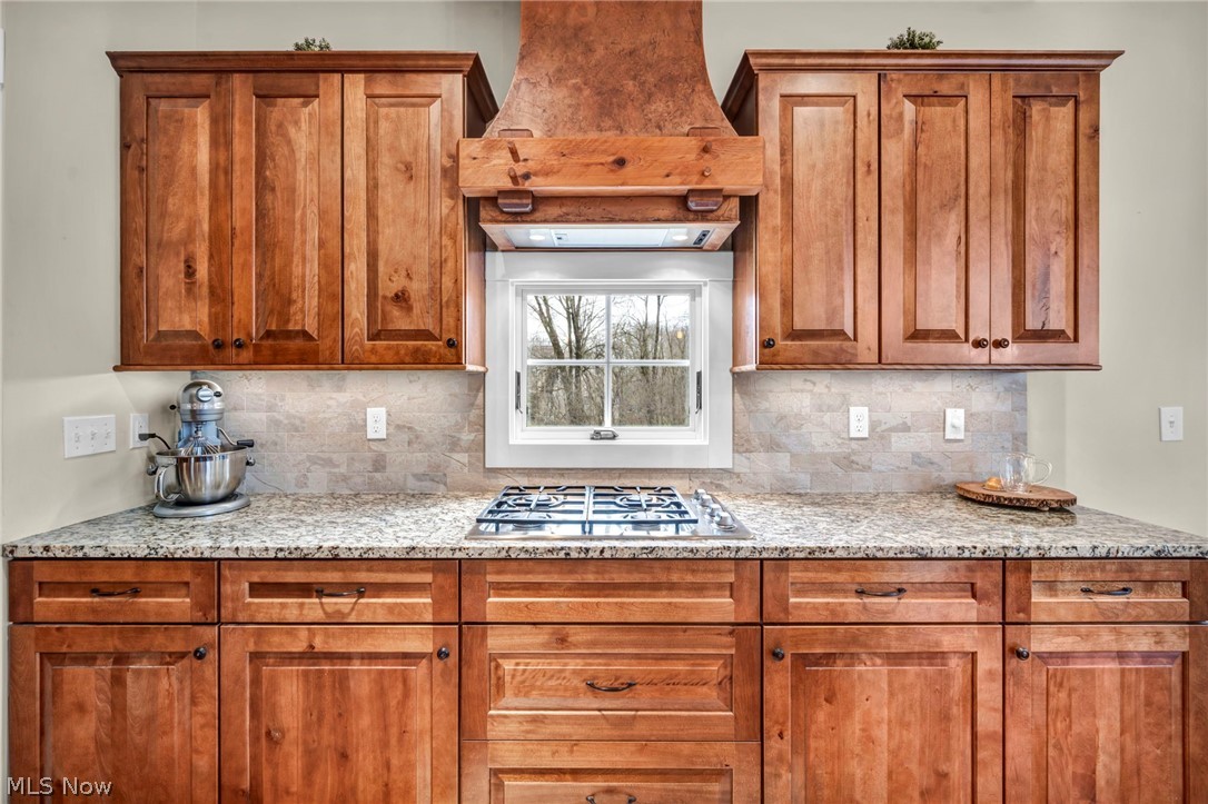 11295 Sutton Place Chardon, OH 44024 - Photo 12 of 50 Kitchen with wood finish cabinetry, decorative backsplash, light stone counters, and stainless steel gas stovetop