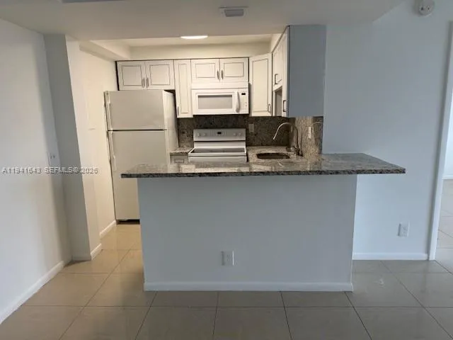 a kitchen with stainless steel appliances granite countertop a refrigerator a stove a sink and white cabinets