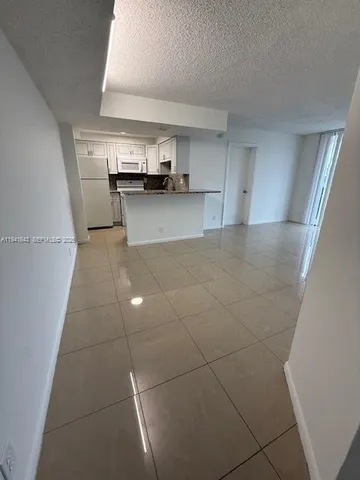 a view of kitchen and empty room with wooden floor
