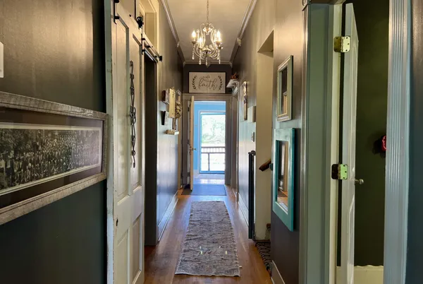 a view of a hallway with wooden floor and a bathroom