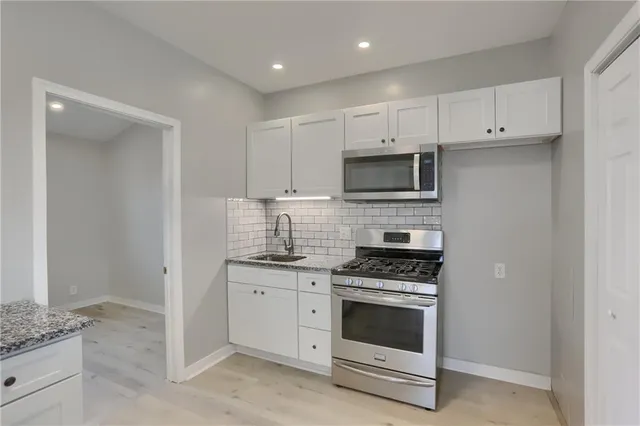 a kitchen with granite countertop white cabinets and stainless steel appliances