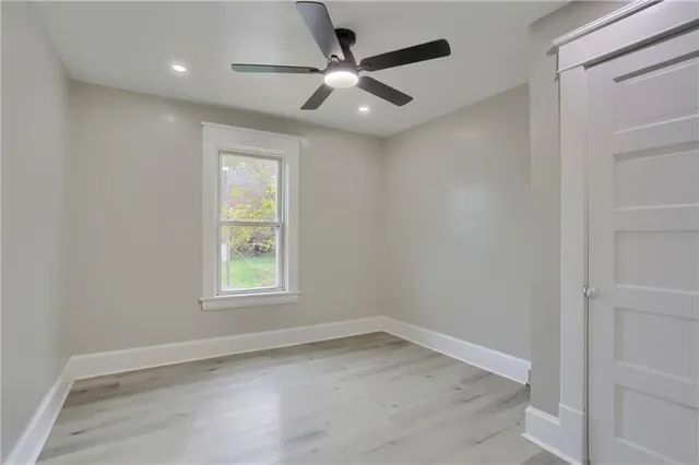 an empty room with a window and a ceiling fan